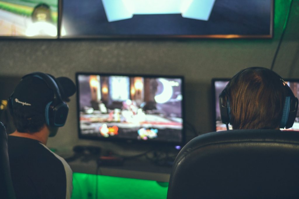 selective focus photography of two persons playing game in front of monitors