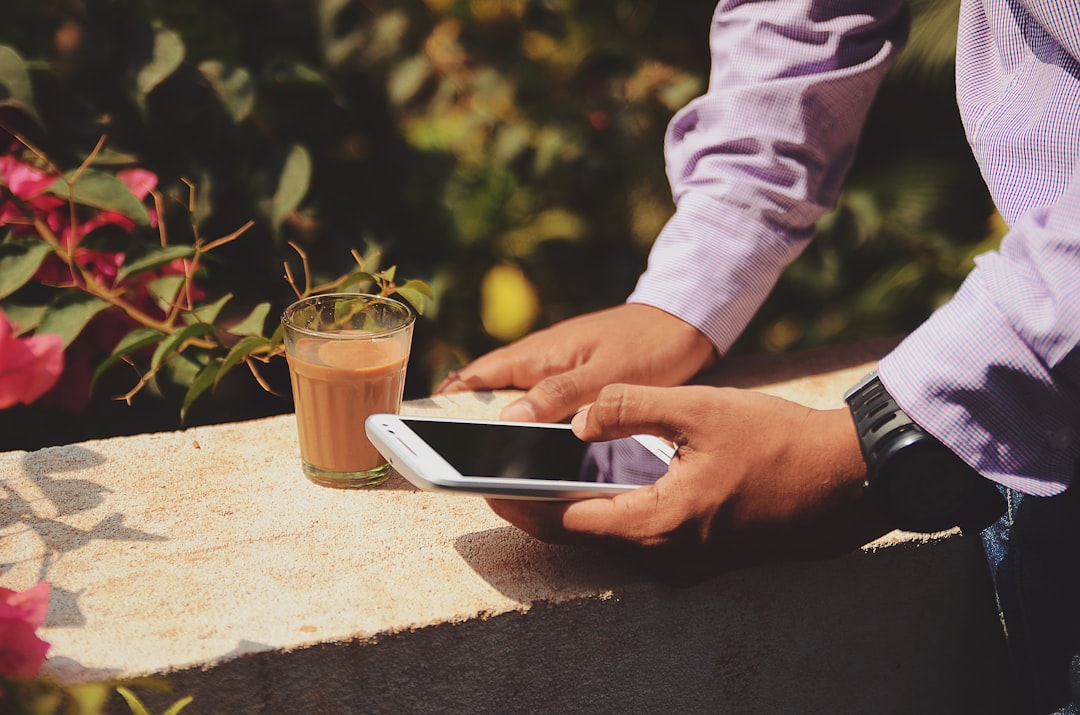 Businessman with coffee outdoors by Games Like man using smartphone beside drinking glass