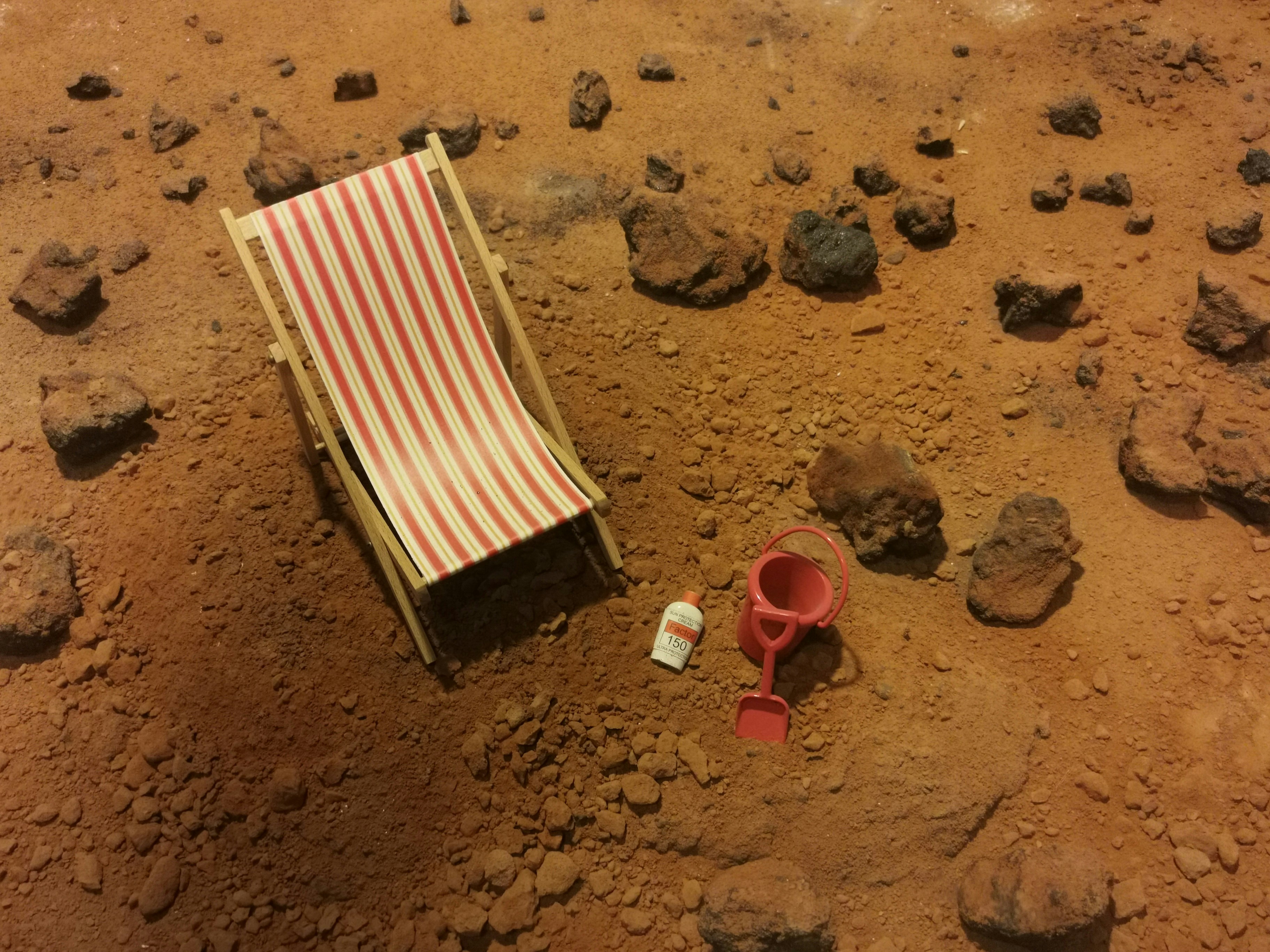 Mars planet, beach lounger by Games Like red and white striped folding bed on brown sand